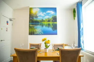 a dining room with a table and a painting of a lake at Lucky Home 15 - Ideal for Trade & Family - 2 Bedrooms - 2 Beds - Max 4 Guests - Close to BAE, Docks, Lake District, Beaches in Barrow in Furness