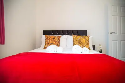 a bed with a red blanket and four towels at Lucky Home 15 - Ideal for Trade & Family - 2 Bedrooms - 2 Beds - Max 4 Guests - Close to BAE, Docks, Lake District, Beaches in Barrow in Furness