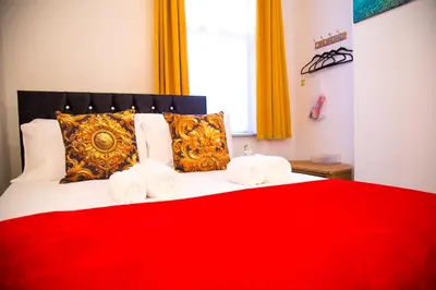 a bedroom with a red bed with towels on it at Lucky Home 15 - Ideal for Trade & Family - 2 Bedrooms - 2 Beds - Max 4 Guests - Close to BAE, Docks, Lake District, Beaches in Barrow in Furness