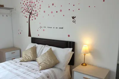 a bedroom with a bed with a tree on the wall at The Moray House in Blackpool