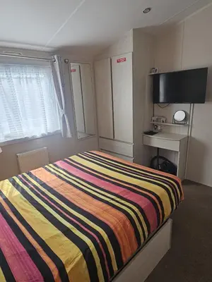 a bedroom with a bed with a colorful striped blanket at Caravan to Hire - CalaGran Fleetwood Blackpool in Fleetwood