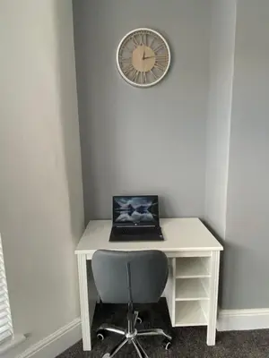 a desk with a laptop and a clock on a wall at Flat2 large modern King Bed Flat, private bathroom Ryan's place in Walton on the Hill