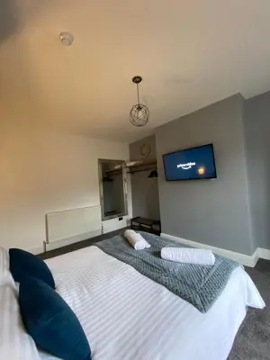 a bedroom with a bed with a tv on the wall at Flat2 large modern King Bed Flat, private bathroom Ryan's place in Walton on the Hill