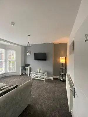 a living room with a couch and a tv at Flat2 large modern King Bed Flat, private bathroom Ryan's place in Walton on the Hill