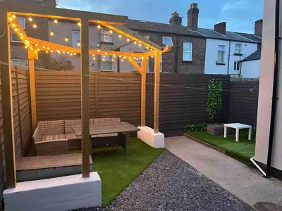 a patio with a bench under a pergola with lights at Flat2 large modern King Bed Flat, private bathroom Ryan's place in Walton on the Hill