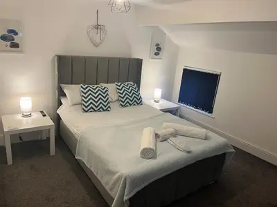 a bedroom with a bed and two tables and a window at Flat3 large modern king Bed flat private bathroom ryan's place in Walton on the Hill