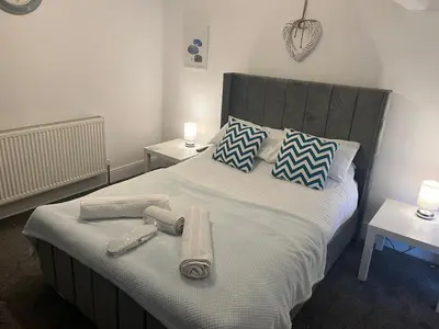 a bedroom with a bed with towels and two tables at Flat3 large modern king Bed flat private bathroom ryan's place in Walton on the Hill