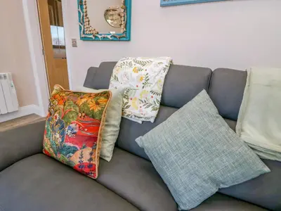 a gray couch with pillows on it in a living room at Elderflower Lodge in Grange Over Sands