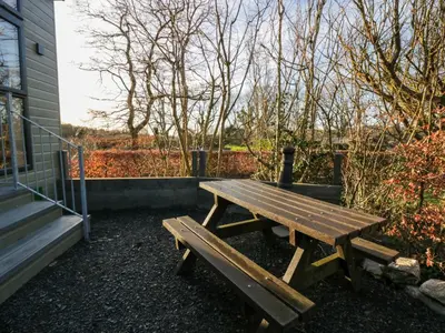 a wooden picnic table sitting next to a building at Elderflower Lodge in Grange Over Sands
