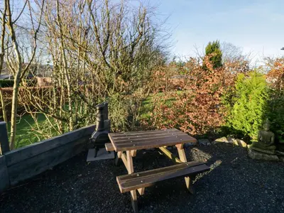 a wooden picnic table and bench in a garden at Elderflower Lodge in Grange Over Sands