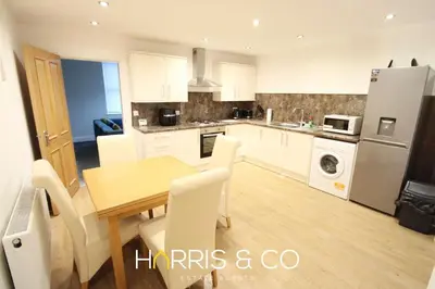 a kitchen with a wooden table and white cabinets at Fishermans Rest in Fleetwood