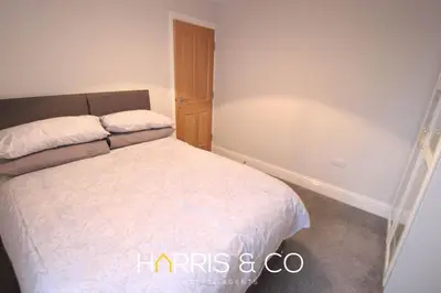a small bedroom with a bed with white sheets at Fishermans View in Fleetwood