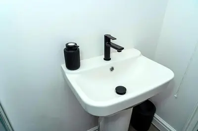 a white sink in a white bathroom with a black bottle on it at Sleek Apartment in Blackpool, Beach View, WiFi, Sleeps 6 in Blackpool