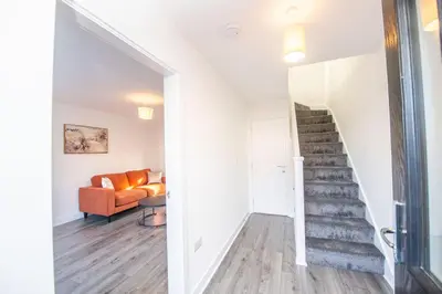 a living room with a staircase and an orange couch at Modern 3-Bed Home-Liverpool Stay in Sefton