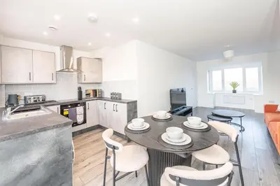 a kitchen and living room with a table and chairs at Modern 3-Bed Home-Liverpool Stay in Sefton