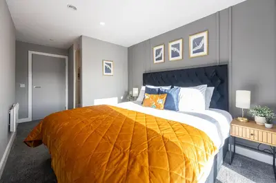 a bedroom with a large bed with an orange blanket at Stunning Liverpool Dockside Apt by City SuperHost in Liverpool