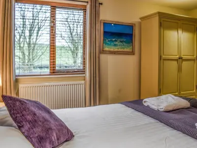 a bedroom with a bed with purple pillows and a window at Sailing By in Carnforth
