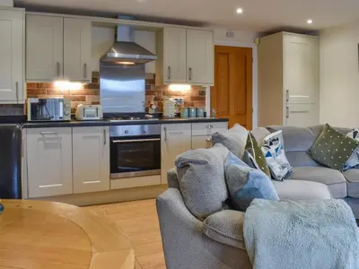 a living room with two couches and a kitchen at Sailing By in Carnforth