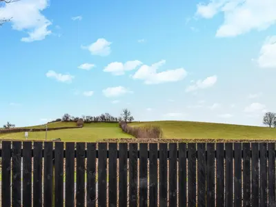 a hill behind a fence with a field in the background at Sandpiper in Carnforth