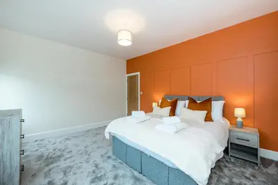 a bedroom with a large bed with an orange wall at Lund House in Ulverston