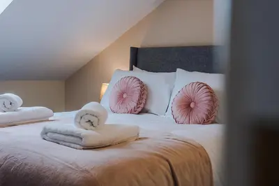a bedroom with a large bed with towels and pillows at Lund House in Ulverston
