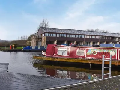 a red boat is docked next to a building at Waterside Retreat in Carnforth