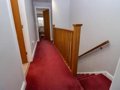 a hallway with a red carpet and a stairway at 9 Swan House in Carnforth