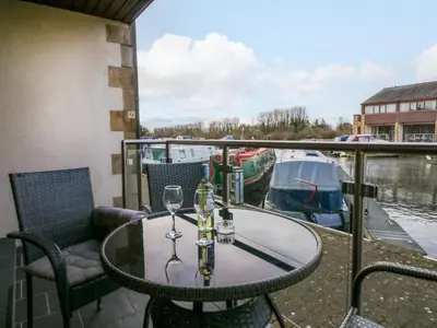 a table with wine glasses on a balcony with a boat at 9 Swan House in Carnforth