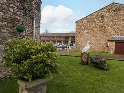 a white bird sitting on a stump in a yard at 9 Swan House in Carnforth
