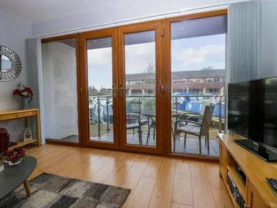 a living room with sliding glass doors with a balcony at 9 Swan House in Carnforth