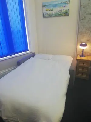 a white bed in a room with a window at Camelot Seafront Hotel in Blackpool