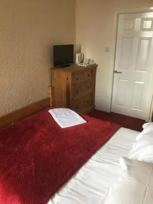 a bedroom with a bed and a tv on a dresser at Camelot Seafront Hotel in Blackpool
