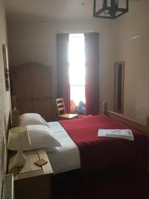 a bedroom with a bed with a red blanket and a window at Camelot Seafront Hotel in Blackpool