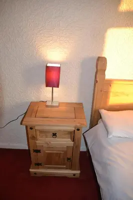 a nightstand with a lamp on it next to a bed at Camelot Seafront Hotel in Blackpool