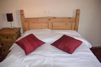 a white bed with two red pillows on it at Camelot Seafront Hotel in Blackpool