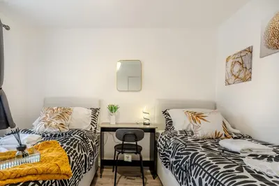 a bedroom with two beds and a desk with a chair at 5-Beds in Quiet Three Bedroom House Near Anfield Stadium, free Parking in Liverpool