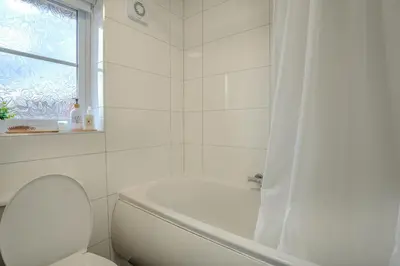 a white bathroom with a toilet and a shower at 5-Beds in Quiet Three Bedroom House Near Anfield Stadium, free Parking in Liverpool