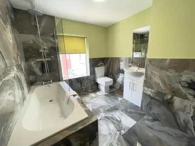 a large bathroom with a tub and a sink at Serenity Holiday Apartments in Blackpool