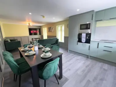 a living room with a table and green chairs at Serenity Holiday Apartments in Blackpool