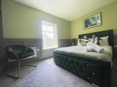a bedroom with a bed and a chair and a window at Serenity Holiday Apartments in Blackpool