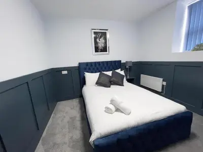 a bedroom with a blue bed with two pillows at Serenity Holiday Apartments in Blackpool