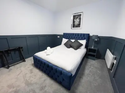 a bedroom with a blue bed with pillows on it at Serenity Holiday Apartments in Blackpool