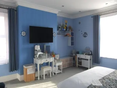 a bedroom with a blue wall with a tv and a desk at FourRooms - Couples Only in Blackpool