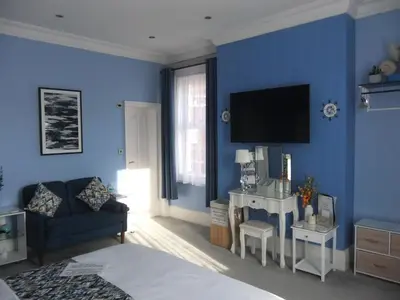 a blue room with a couch and a tv at FourRooms - Couples Only in Blackpool
