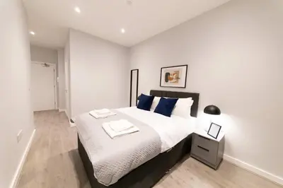 a bedroom with a large bed with blue pillows at Convenient 2 Bed Apartment in Waterloo Liverpool in Waterloo