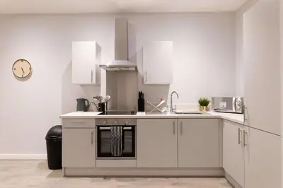 a kitchen with white cabinets and a sink at Convenient 2 Bed Apartment in Waterloo Liverpool in Waterloo