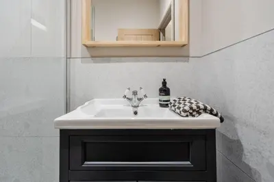 a bathroom sink with a bottle of wine on it at Charlottes Place in Liverpool