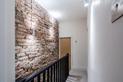 a hallway with a brick wall and a staircase at Charlottes Place in Liverpool