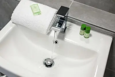 a bathroom sink with a faucet with water coming out at Picasso's Place Liverpool Apt Sleeps 9 in Liverpool