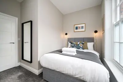 a bedroom with a large bed and a mirror at Picasso's Place Liverpool Apt Sleeps 9 in Liverpool